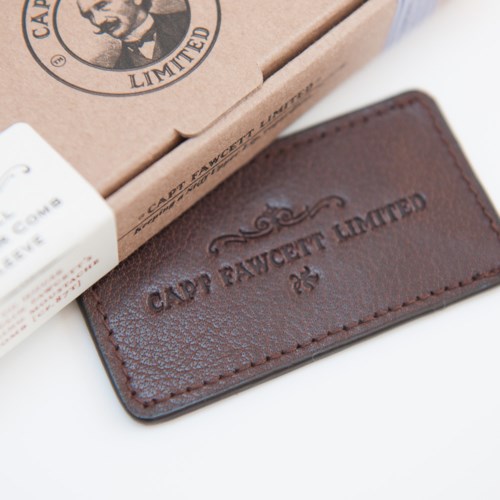 Läderbricka med präglad text 'CAPPY BAUWET LIMITED' och dekorativ design.