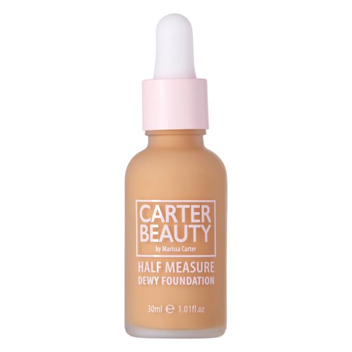 En liten flaska foundation med pipett, rosa lock och etikett som säger 'Carter Beauty Half Measure Dewy Foundation.'