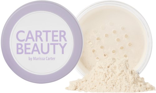 Ett runt lock med etiketten 'Carter Beauty.' Gult puder spillr ut, vilket indikerar en kosmetisk produkt.