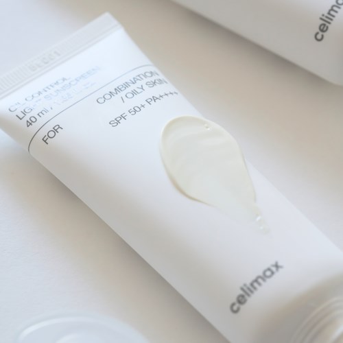 Een witte tube met crème en zwarte tekst, geplaatst op een witte ondergrond, waarschijnlijk een huidverzorgingsproduct.