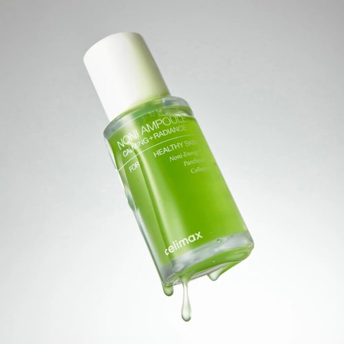 A green bottle with a white cap, containing skincare product with droplet at the bottom.