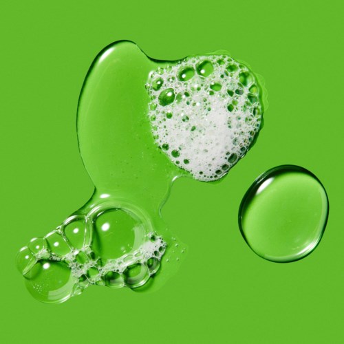 Eine grüne Flüssigkeit mit Bläschen und einem runden Tropfen vor grünem Hintergrund.