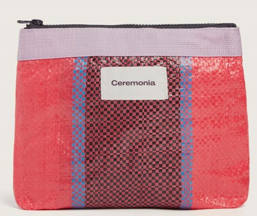En liten väska med rosa, lila och svart rutigt och randigt mönster, och en vit etikett som säger "Ceremonia."