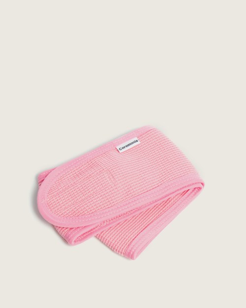 Een gevouwen roze elastische band of riem, mogelijk een sport- of medisch item, op een effen achtergrond.
