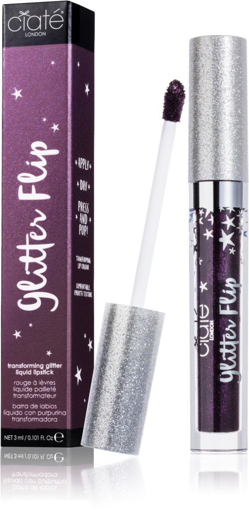 En lila glitterläppstift med silverlock, bredvid sin lila förpackning med stjärnor och text.