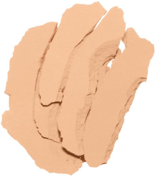 En beigefärgad makeupprodukt, troligtvis ett pressat puder eller foundation, i en trasig, ojämn form.