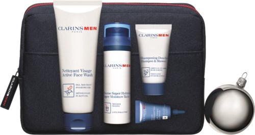 Set med Clarins Men hudvårdsprodukter i en svart väska, inklusive ansiktsrengöring, toner och kräm, med en silverprydnad i närheten.