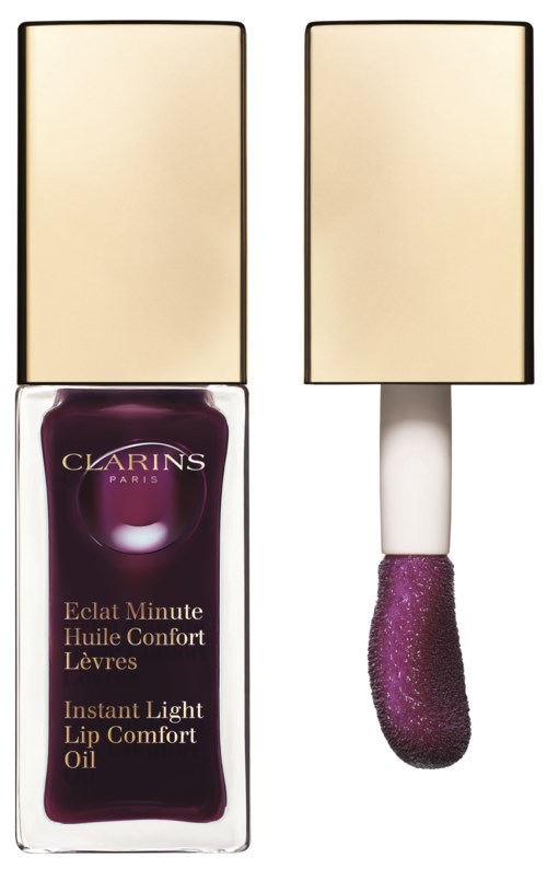 En flaska Clarins läppolja med en lila applikatorborste bredvid.