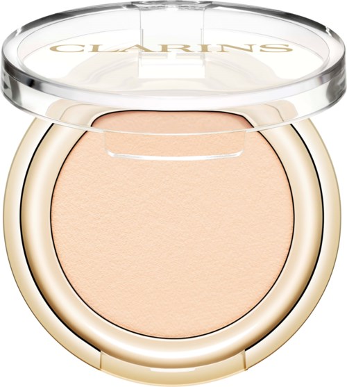 En kompakt av ljusbeige pressad puder med klart lock och guldaccenter på sidan.