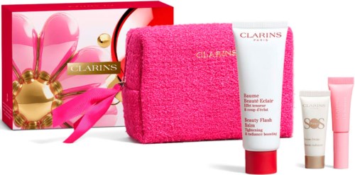 Skönhetspresentset med Clarins produkter, en rosa handduk och en dekorativ rosa och gul box.