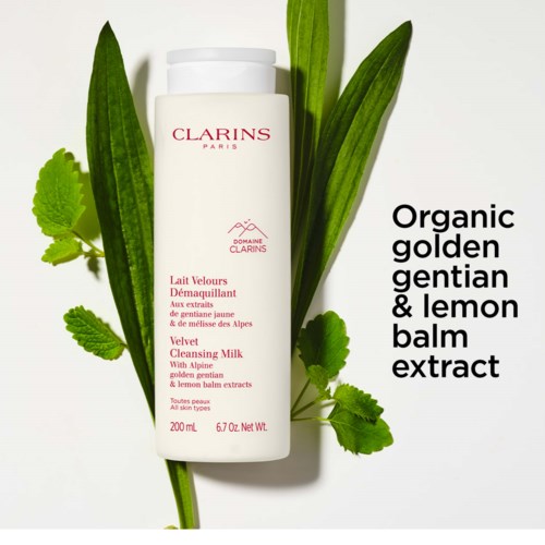 En vit flaska märkt Clarins, omgiven av gröna blad, med text om ekologisk citronmeliss och rengöringsmjölk.