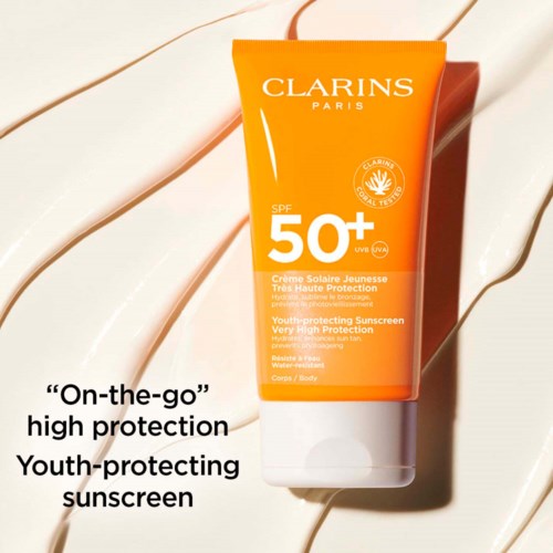Orange solkrämstubbe med SPF 50+, Clarins-märke och text om högt skydd och ungdomsvård.