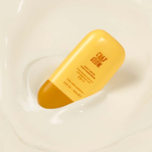 Gul flaska märkt 'Clay Glow' badprodukt i ett vitt badkar med vatten.