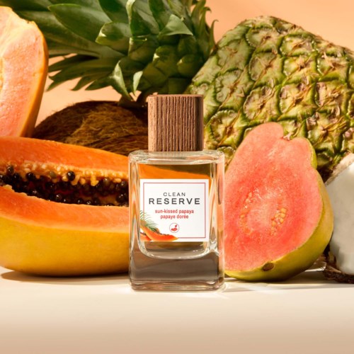 En parfymeflaske merket Clean Reserve med tropisk frukt som papaya og ananas rundt den.
