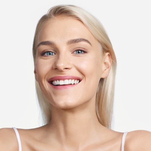 En ung kvinde med langt blondt hår, lyseblå øjne og et stort smil, iført en hvid top.