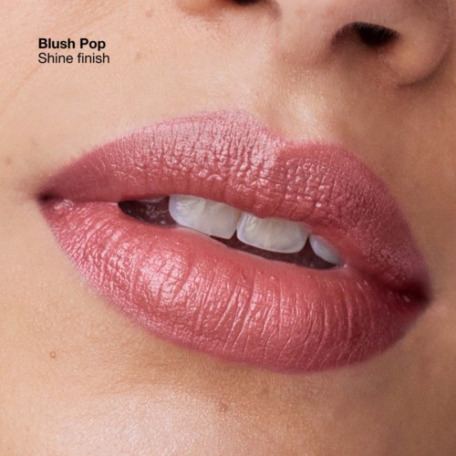 Close-up of lips with pink lipstick, slightly open, showing teeth and a hint of tongue.
