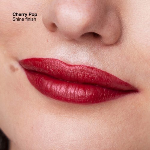 Close-up of lips with bright red lipstick called Cherry Pop, shiny finish, and smooth skin nearby.