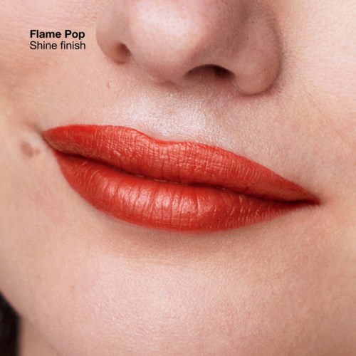 Close-up of lips with shiny red lipstick and part of nose above, with text about Flame Pop shine finish.