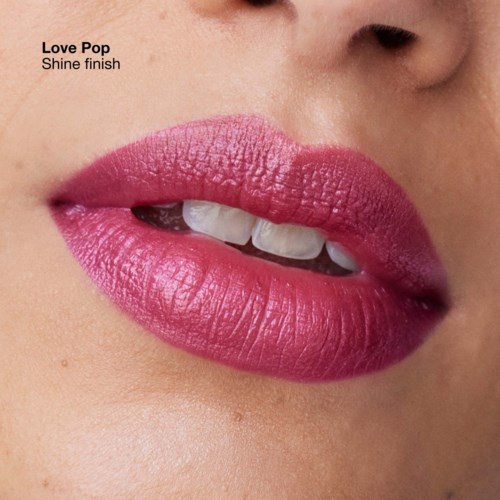 Close-up of lips with pink lipstick, slightly parted showing teeth, with text about Love Pop lipstick shade.