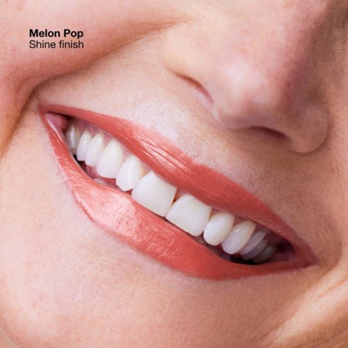 A close-up of a smiling person with white, bright teeth and peach-colored lips. The text says 'Melon Pop Shine finish.'
