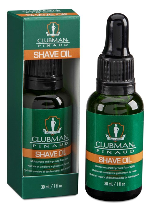 En liten grön flaska med droppklar top, märkt 'Clubman Pinaud Shave Oil', står bredvid sin box. Boxen är också grön och orange.