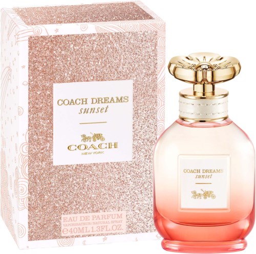 Różowa butelka perfum z złotym korkiem i pasujące opakowanie z napisem Coach Dreams Sunset.