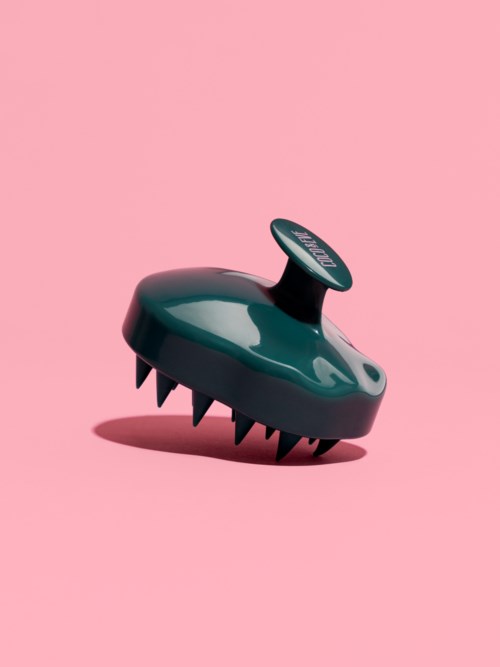 A black device with sharp teeth and a round button on top, set against a pink background.