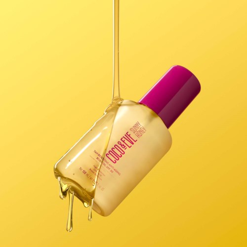 Eine Flasche mit der Aufschrift 'Coco Beach Summer', gelbe Flüssigkeit fließt heraus, vor gelbem Hintergrund.