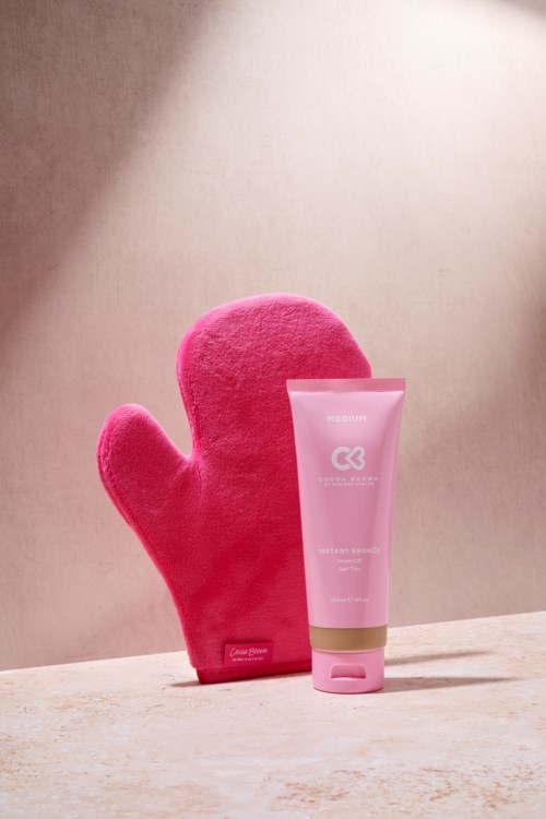 En rosa plyschhandske och en tub med rosa hudvårdsprodukter på en ljus yta. Bakgrunden är enkel och mjuk.