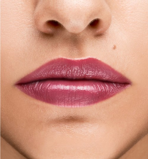 Close-up of lips with pink lipstick and small mole above upper lip.