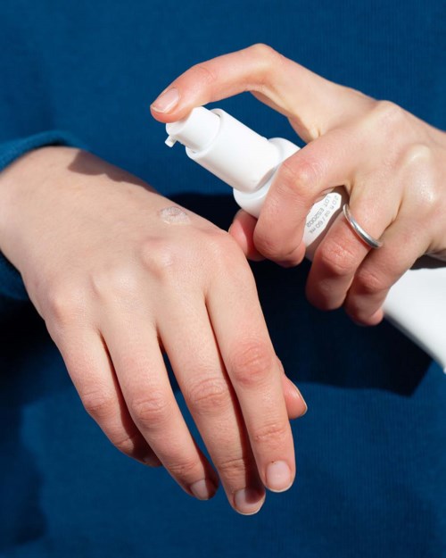 En person påfører lotion eller antiseptisk middel på en annen persons hånd.