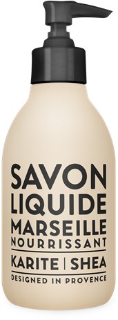 En beige flaska med svart pumpsystem, märkt 'Savon Liquide Marseille Nourrissant,' med orden 'Karite' och 'Shea.'
