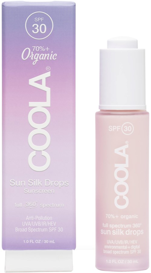 Fioletowe i białe opakowanie z małą różową butelką kremu przeciwsłonecznego o nazwie 'COOLA Sun Silk Drops' z SPF 30.