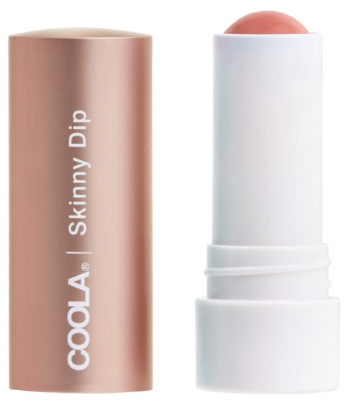 En beige läppbalsamtub med etiketten 'COOLA Skinny Dip' och en vit locka som visar en rosa balsamstång.