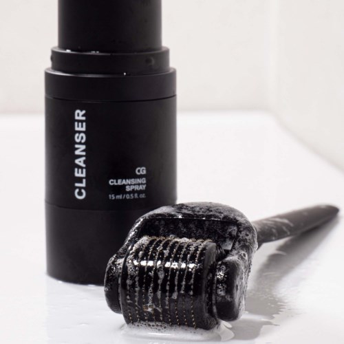 En svart flaska märkt 'Cleanser Cleaning Spray' bredvid en hårroller med skum på.