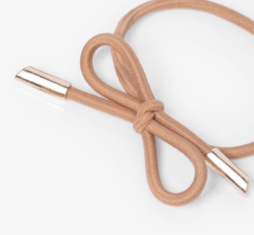 A beige shoelace tied in a bow with metal tips on both ends.