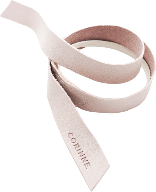 Ett vitt band med namnet "Corinne" på, fint sammanrullat, med en mjuk rosa sida.