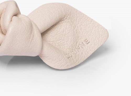 En hand trycker på mjukt lädermaterial, vilket visar uppstämplat text.