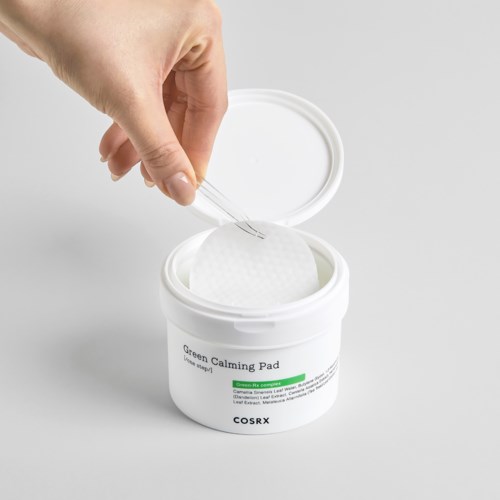 En hand öppnar en behållare med Green Calming Pad hudvårdsprodukt.