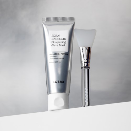 En sølvfarget tube merket 'PDRN EXOSOME Skinplaning Glaze Mask' og en hvit børste står på en hvit overflate.