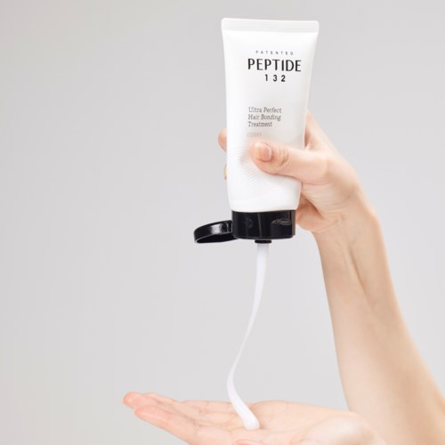 En hand som klämmer ut ett hårvårdsprodukter från ett tube, produkten rinner ut.