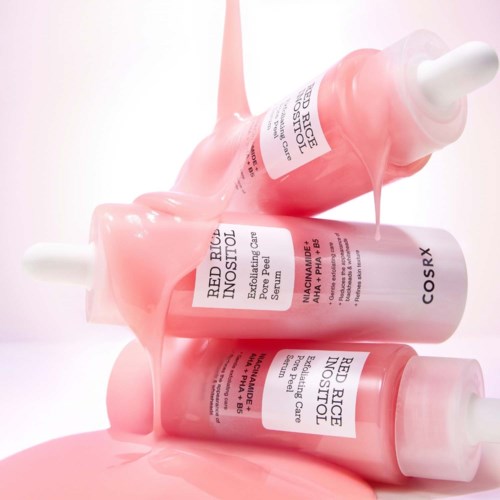 Drei pinke Hautpflege-Serumflaschen mit Tropfenzapfenvakuum, leicht geneigt, mit Serum, das auf eine weiße Oberfläche tropft.