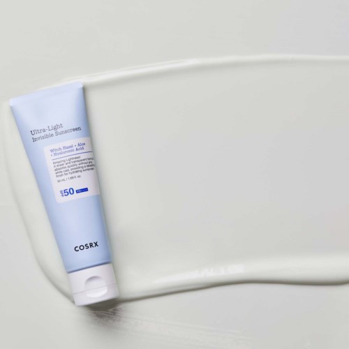 Sininen ja valkoinen aurinkovoideputeli valkoisella pinnalla. Etiketti sanoo 'COSRX Ultra-Light Invisible Sunscreen SPF 50'.