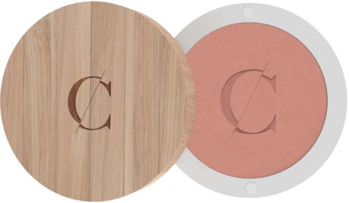 Round wooden box with a letter 'C' cutout on the top, next to a similarly shaped compact with pink powder.
