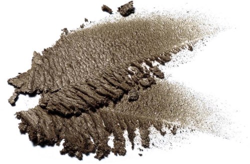 Gray powder spread with textured lines and scattered particles on white background.