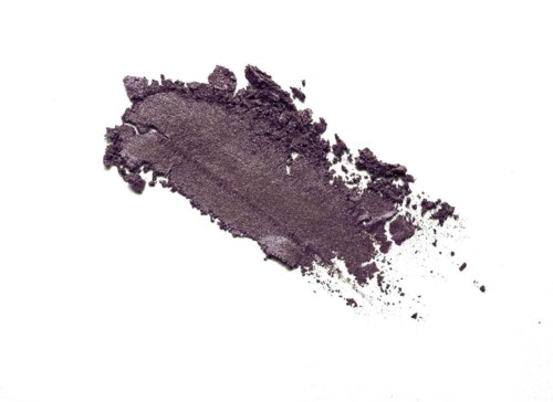Purple eyeshadow smudge with a rough, uneven edge on a white background.