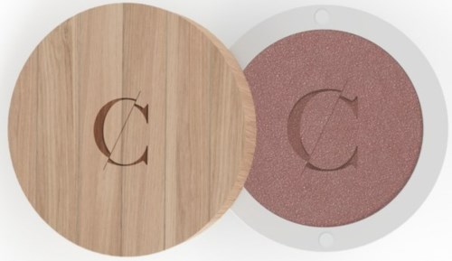 A round wooden container and a pinkish powder in a small white dish with a letter 'C' logo.