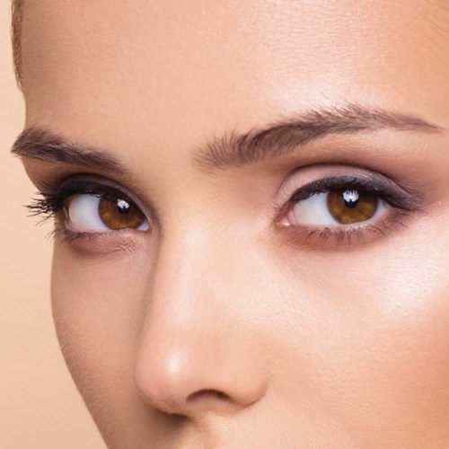 Close-up of a woman's face with brown eyes, light makeup, and smooth skin.
