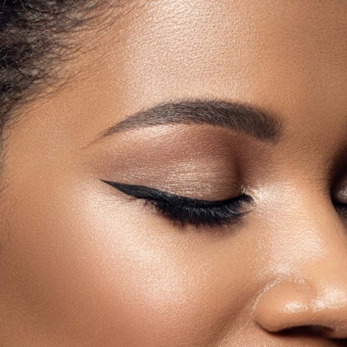 Närbild av en kvinnas ansikte med ögonmakeup, inklusive wingad eyeliner och skimrande ögonskugga.
