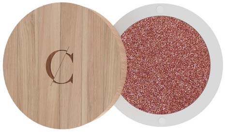 A makeup blush in a compact with a wooden cover and a shiny, reddish-pink center.